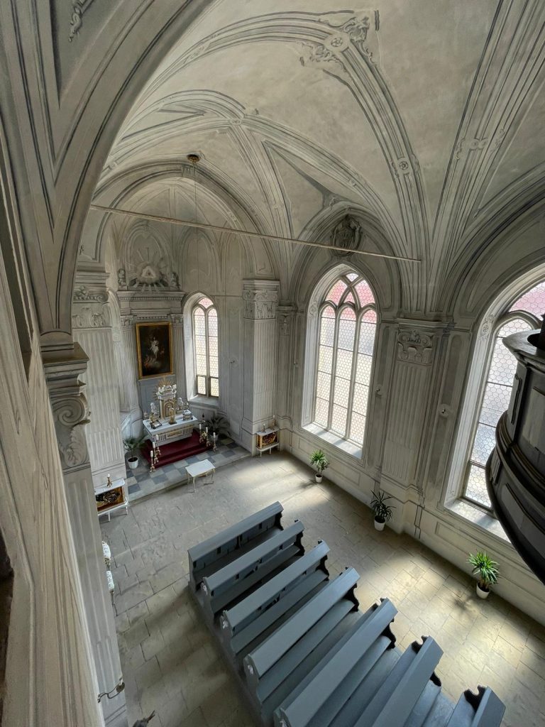 Interiér kaple na zámku v Litomyšli po rekonstrukci, pohled shora na lavice a oltář.