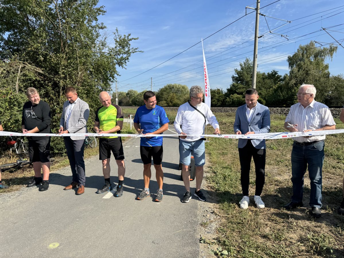 Skupina mužů při slavnostním přestřižení pásky na otevření cyklostezky.