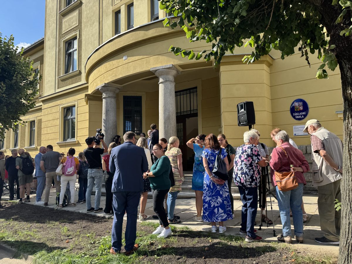 Skupina lidí před vstupem do zrekonstruované základní školy v Chrastavě při slavnostním otevření.