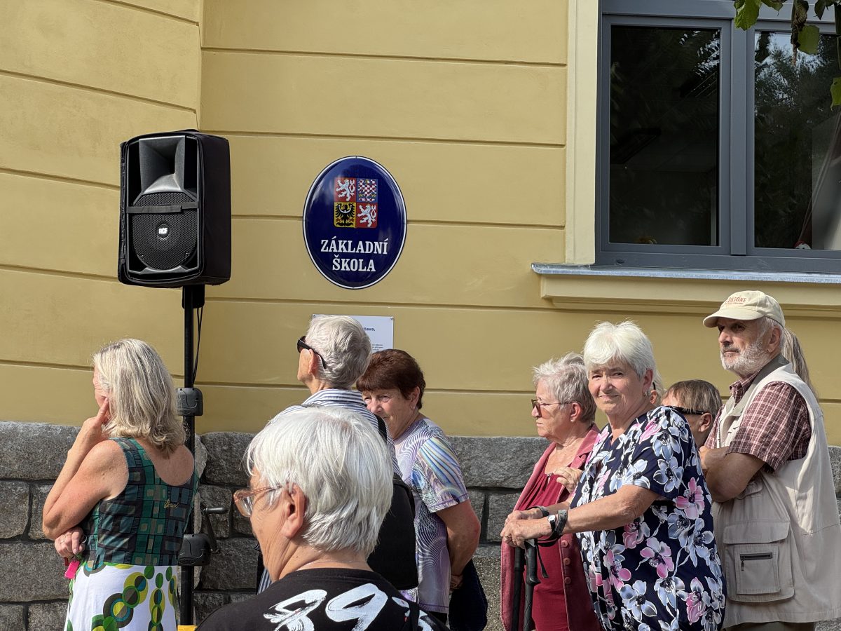 Návštěvníci stojící u budovy s cedulí Základní škola během slavnostního otevření.