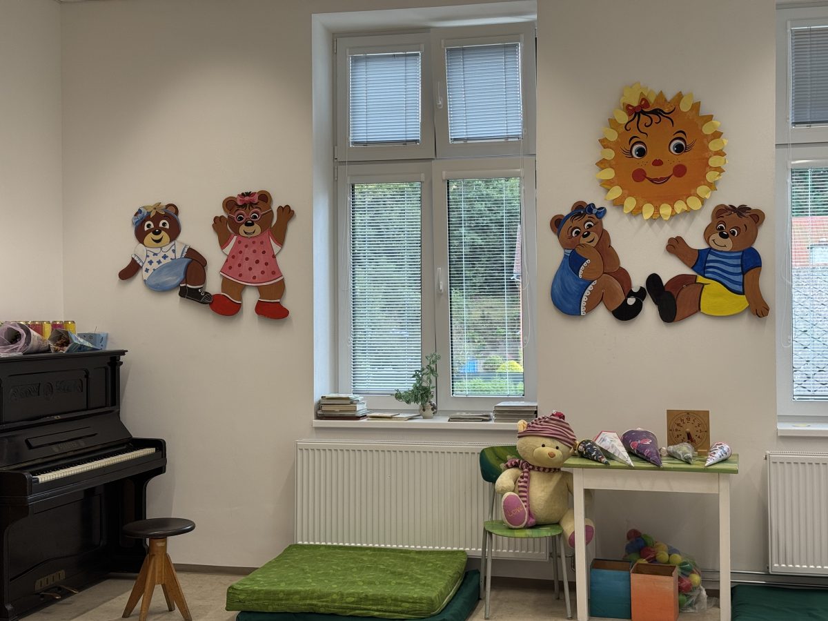 Třída s klavírem, plyšovými hračkami a nástěnnými dekoracemi v podobě medvídků a sluníčka.