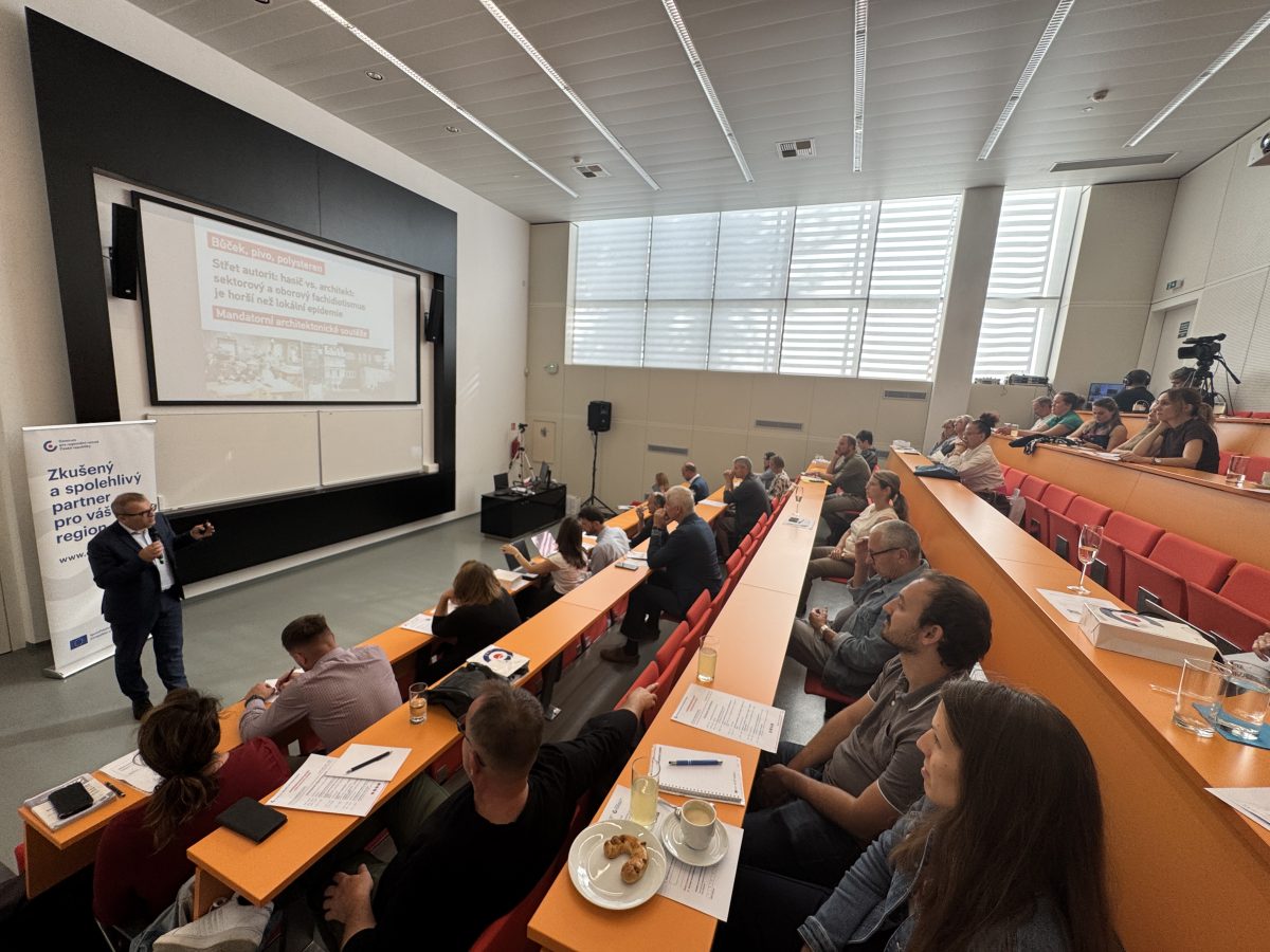 Přednášející na konferenci Architektonická soutěž ve Zlíně mluví k plnému sálu starostů, architektů a odborníků.