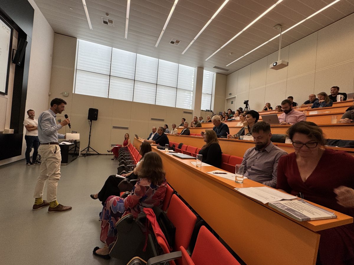 Účastníci konference Architektonická soutěž ve Zlíně sledují prezentaci a debatují s řečníkem.