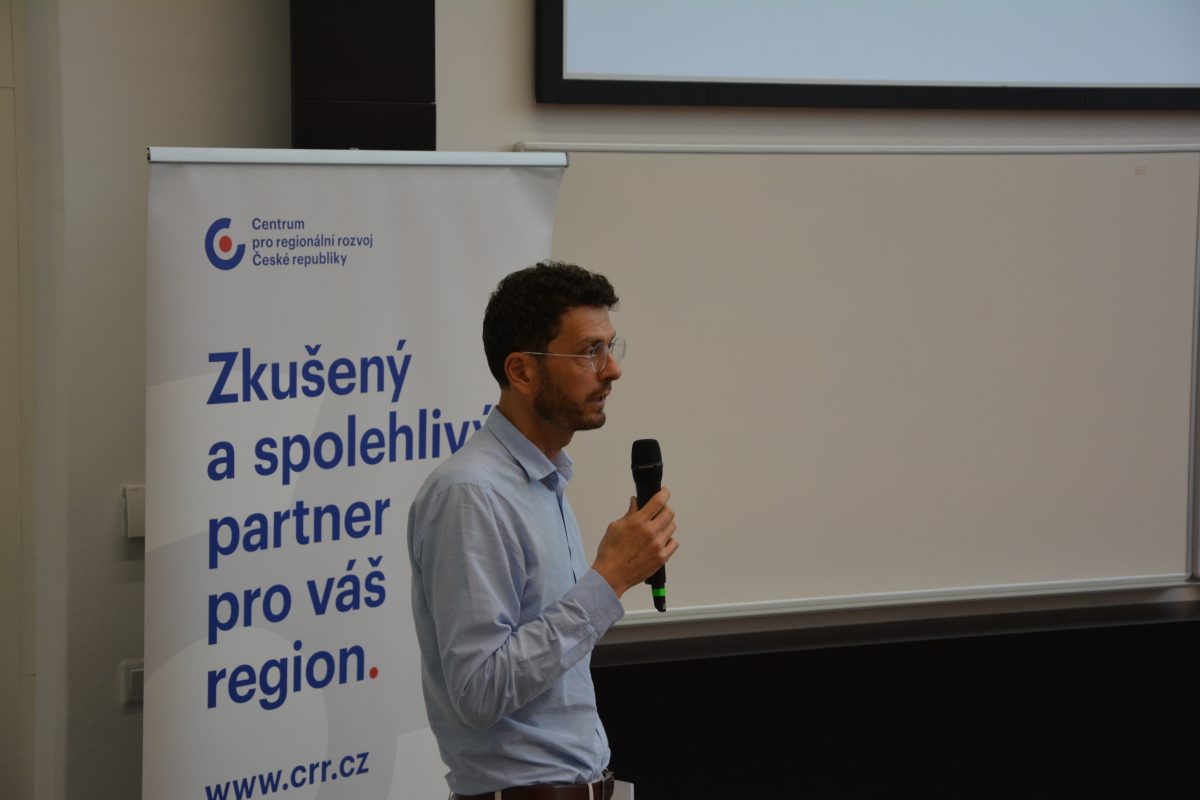 Prezentující před roll-upem Centra pro regionální rozvoj během konference Architektonická soutěž ve Zlíně.