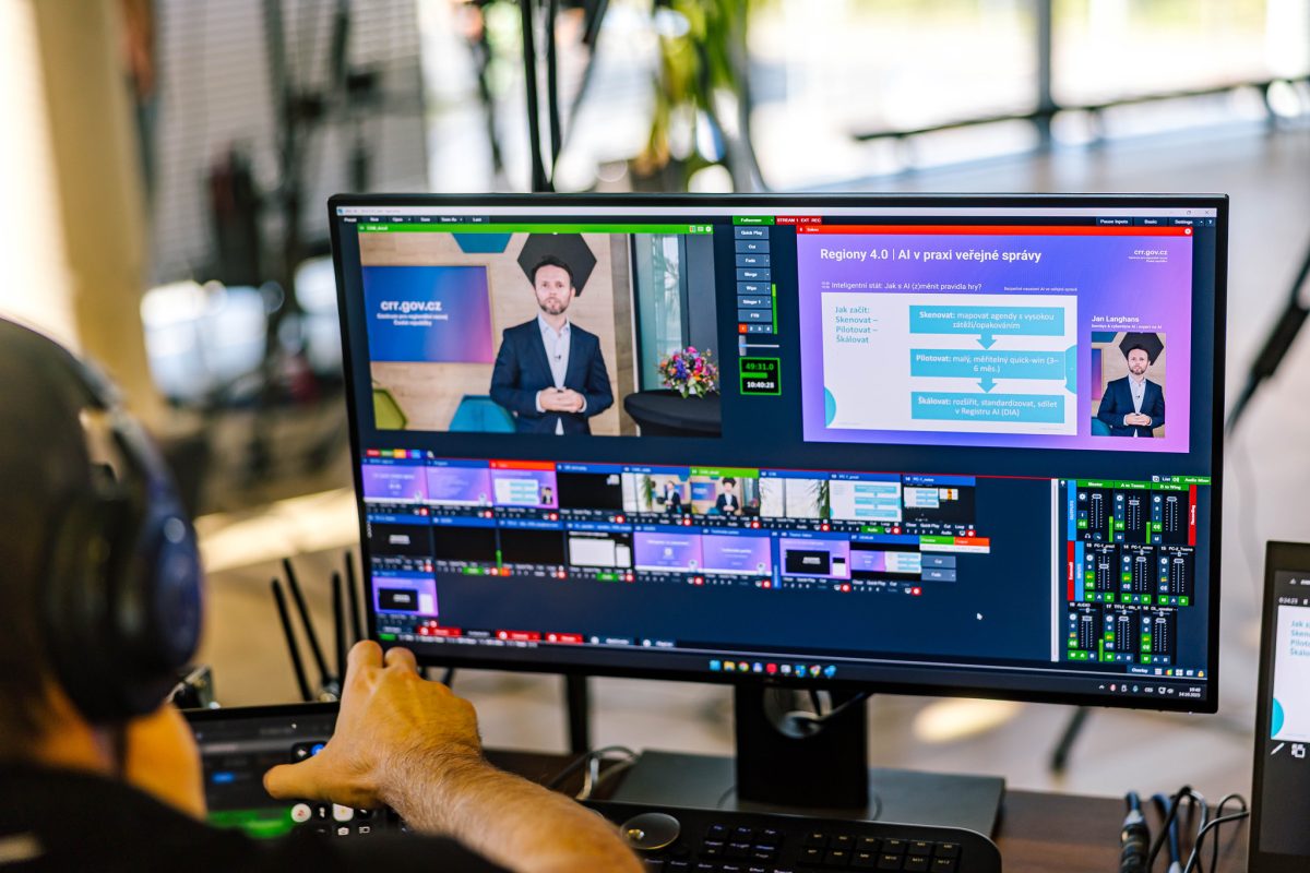Záběr z režie online přenosu, na monitoru probíhá prezentace o umělé inteligenci ve veřejné správě.