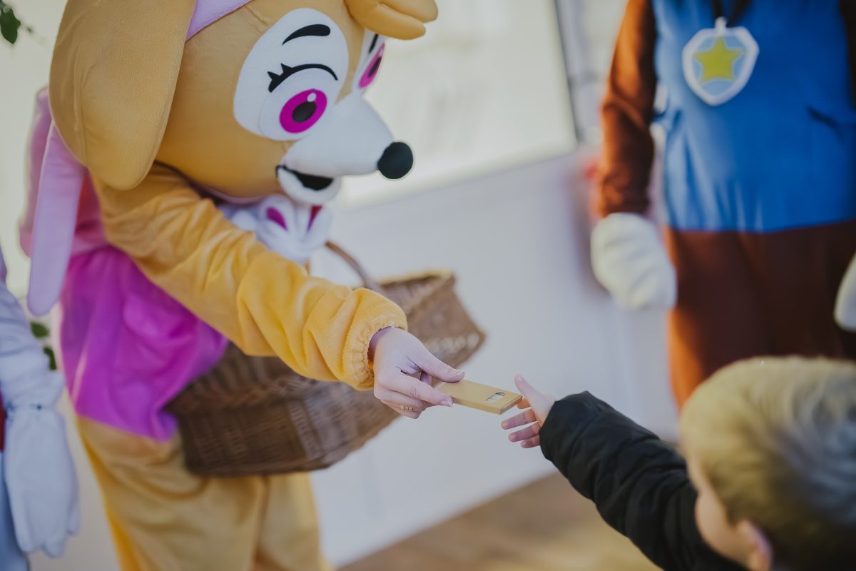 Postavička v kostýmu předává malému dítěti dárek při otevření nové školky Zavadilka v Jaroměři.