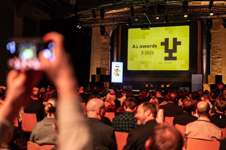 Sál plný diváků sledujících slavnostní vyhlášení AI Awards 2025, na pódiu svítí hlavní projekce s logem akce.
