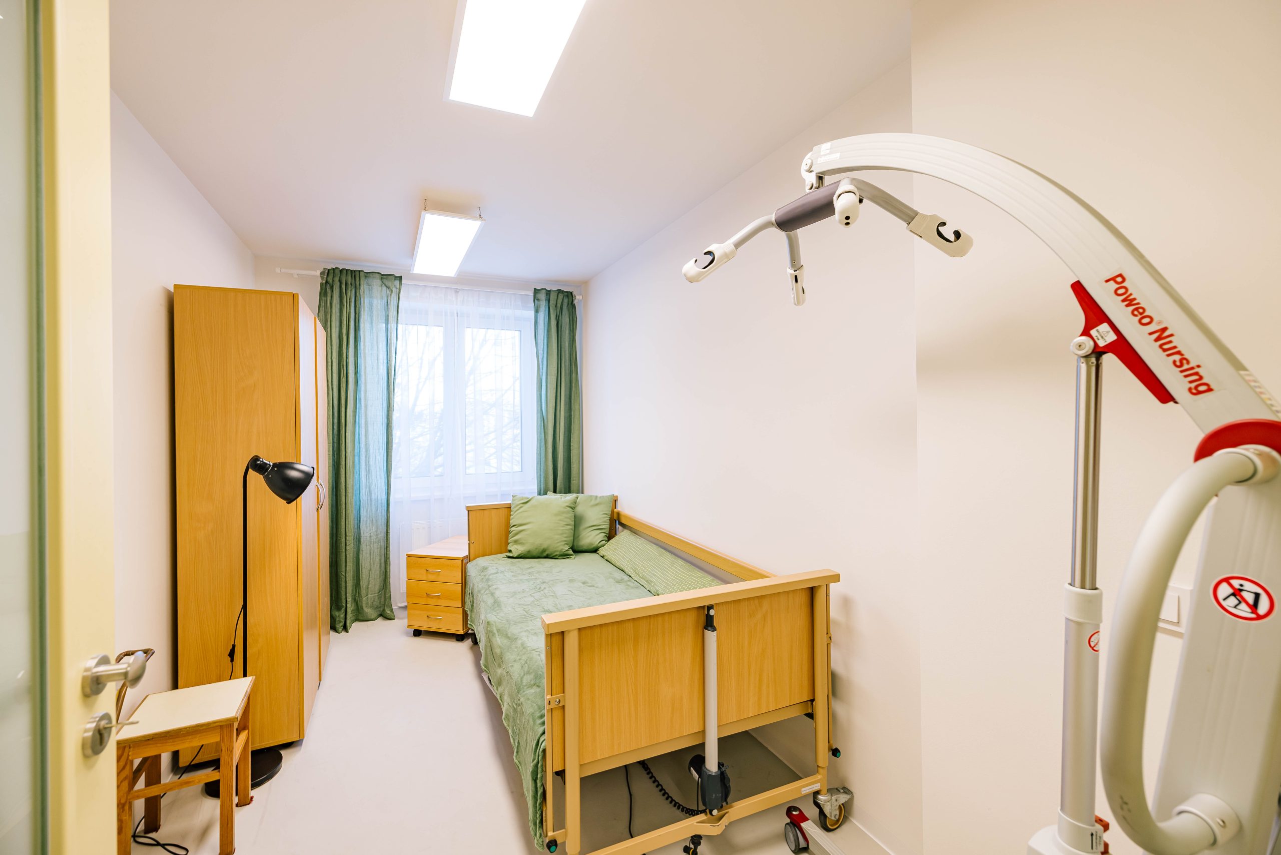 Pokoj s polohovací postelí a zvedacím zařízením, vybavení pro péči o klienty.
